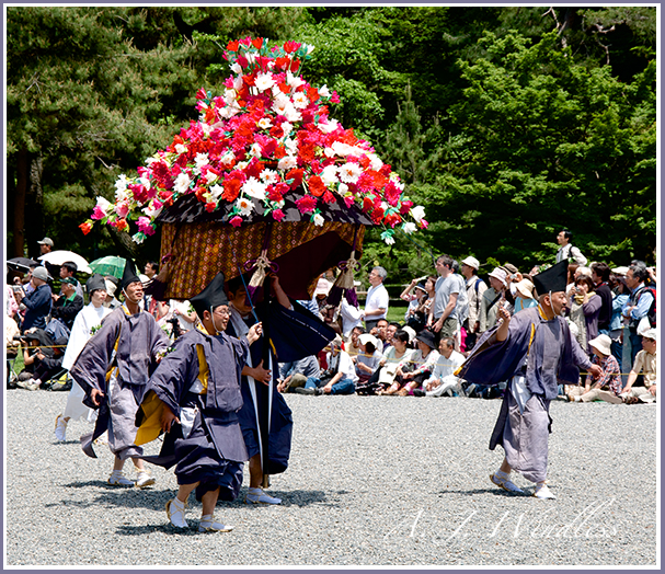 A sight to see in the Kyoto parade as dressed in beautiful traditional clothing these men carry a huge display of flowers.