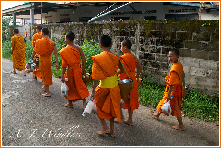 Buddhist monks return from collecting food throughout the village