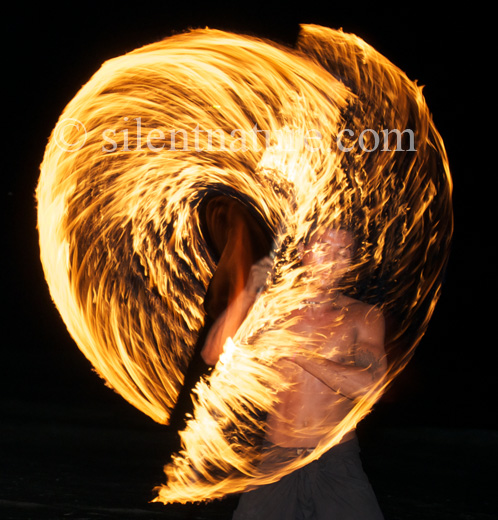 A Thai man dances with fire, swirling flames all around him.