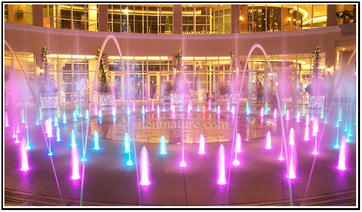 The water fountain lit with colored lights and little arches of water.