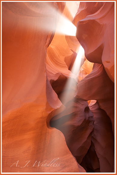 From deep within the beautiful walls of a slot canyon, double beams of light shine down from the sky above.