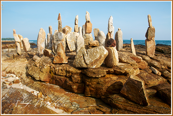 A Thai artist has balanced rocks on top of each other such that it appears goblins have gathered on the beach trying to decide what to do next.