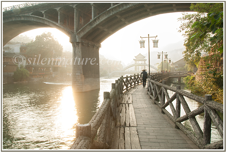 With the morning sun in his face a Chinese man walks to work on a bridge and underneath a bridge.