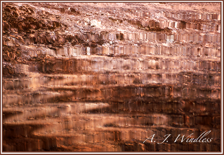 A puddle reflects the colorful walls of Snow Canyon creating a kaleidascope of bronze in its ripples.