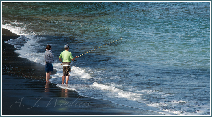 A fisherman stands at the foot of the waves with his loyal wife.