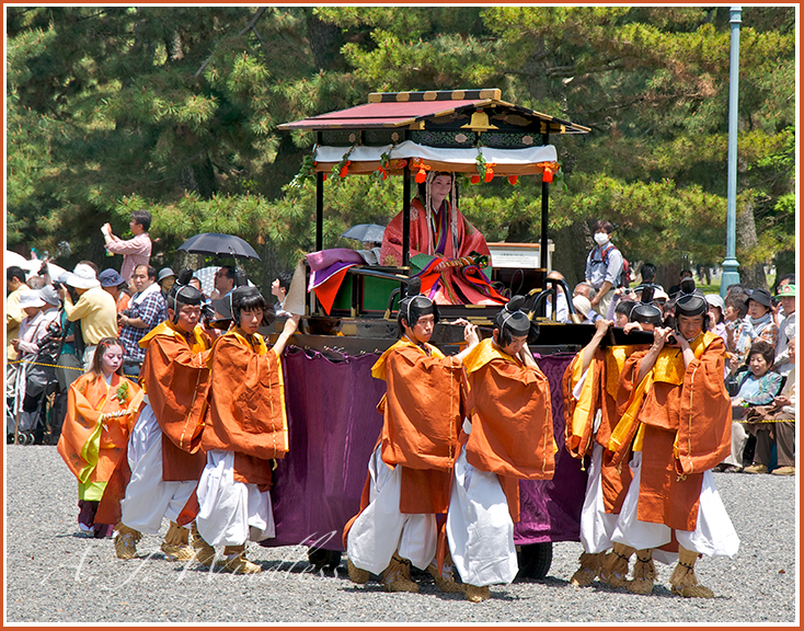 In Japanese costumes from hundreds of years ago, these men carry this woman's carriage in the Kyoto parade.